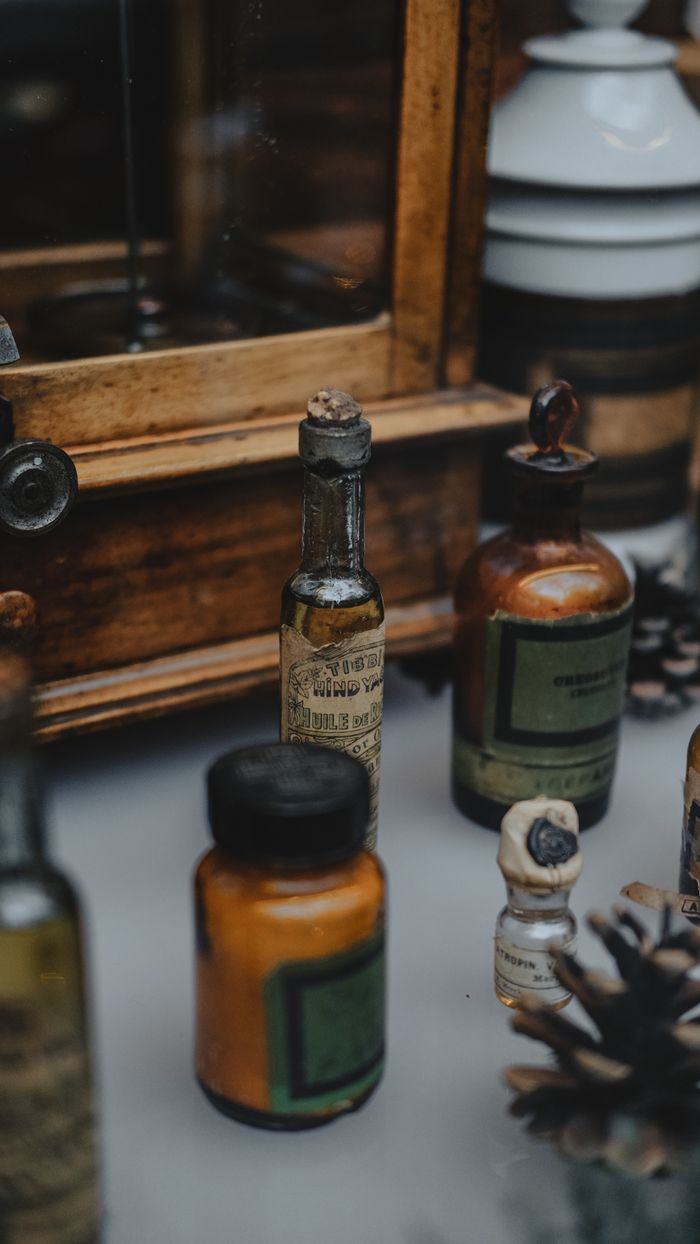 Home A collection of antique apothecary bottles with pine cones on display, creating a rustic vibe.