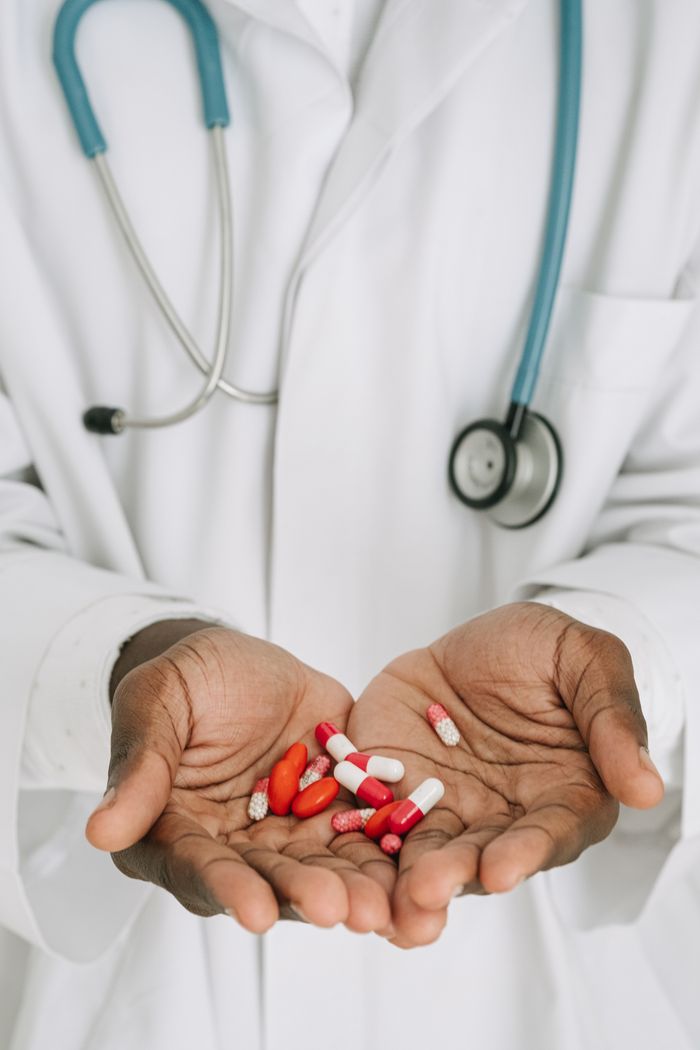 Home A doctor in a medical gown holding capsules, illustrating healthcare concepts.
